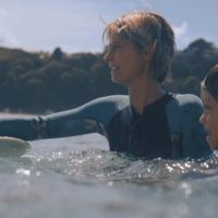 幼い息子と海を楽しむ女性ロングボーダーのアイコン:ベリンダ・バッグス